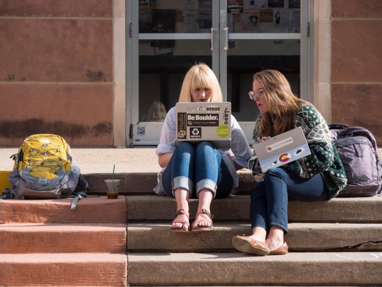 Students sitting outside on campus building steps