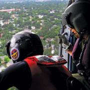 Overhead view of flooding in a community from behind rescue workers inside a helicopter