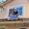 Man installing solar panel on roof of house