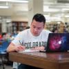 Student sitting at desk in library and writing