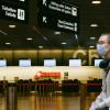 Woman sits in an airport while wearing a mask.