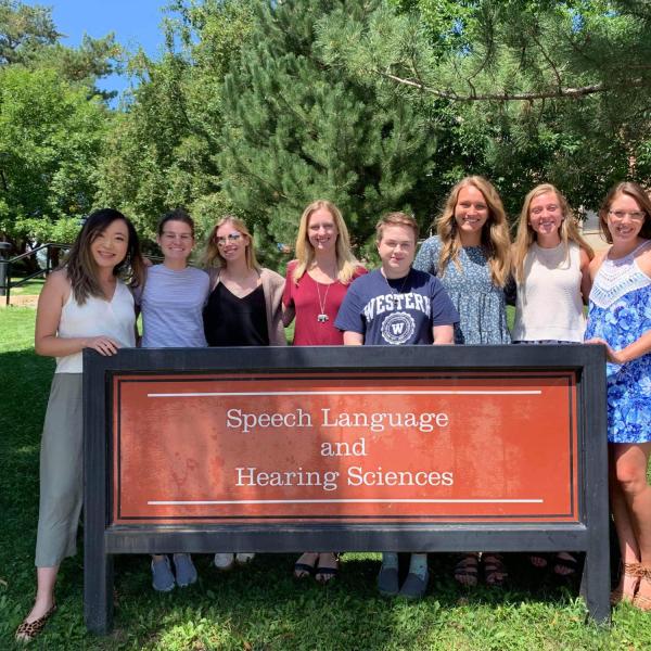 Some of the 2022 AuD students in front of the SLHS sign outside the SLHS building in the summer