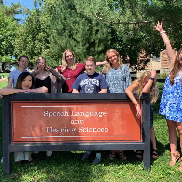 Some of the class of 2022 AuD students in front of the SLHS sign outside the SLHS building with a funny pose