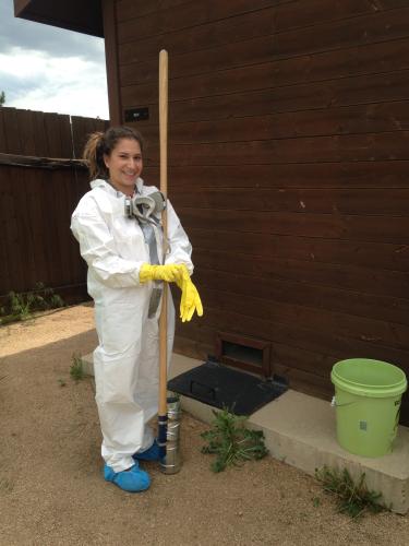 Research in Tyvex and putting on gloves as she is bout to collect sludge
