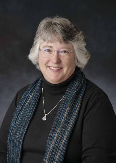 portrait of Dr. Jobin wearing a black sweater and turquoise and black scarf