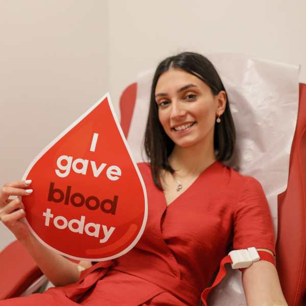Woman donating blood with sign saying "I gave blood today"