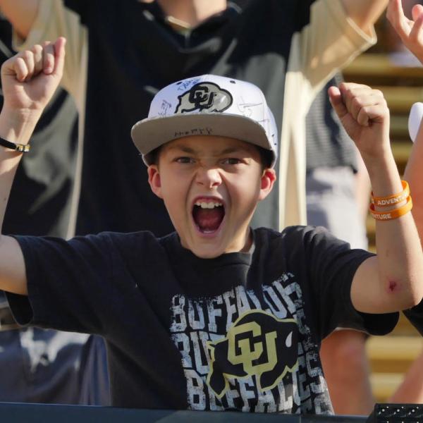 A young male fan in a crowd loudly cheering for CU