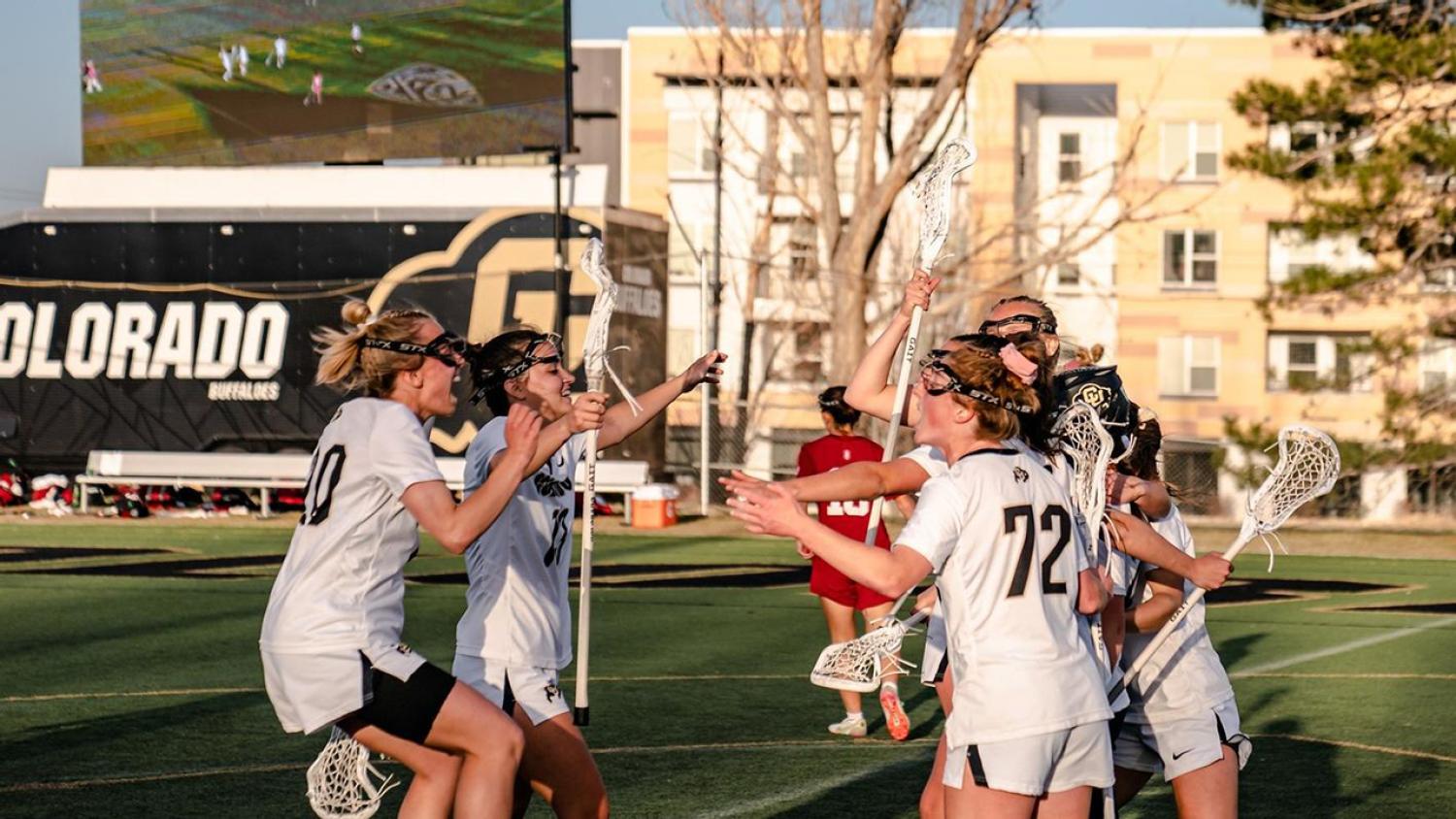 CU women's lacrosse players on the field run towards each other in celebration
