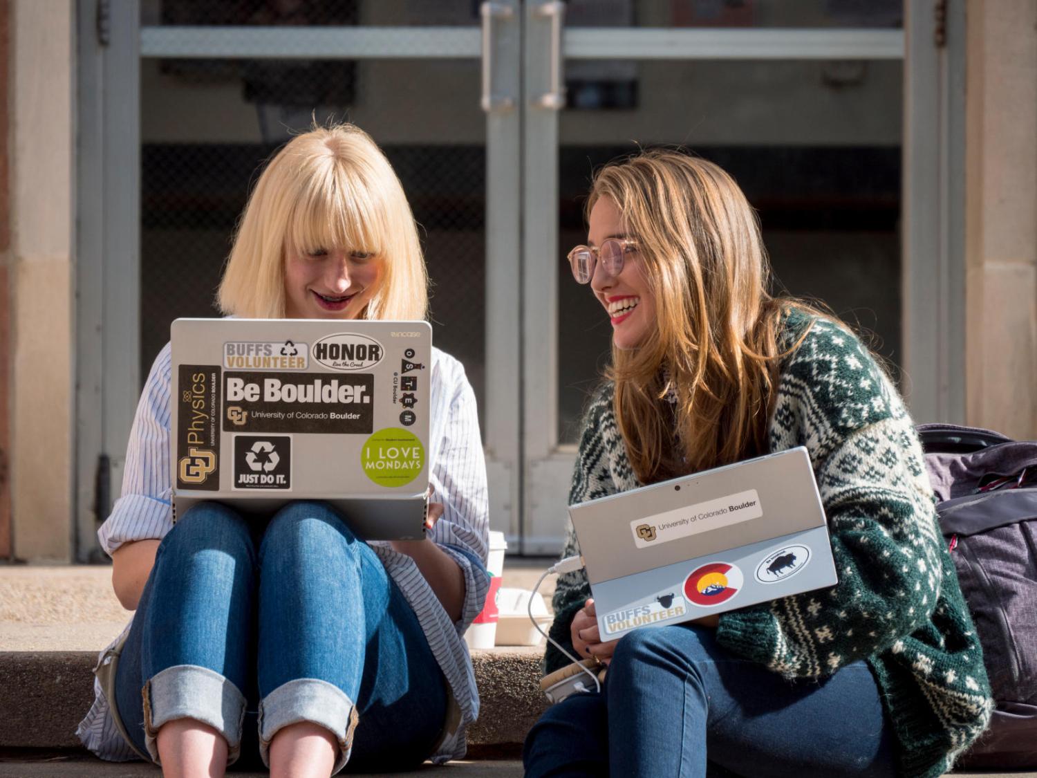 Two women working on their computers together