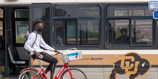 Person riding bike next to Buff Bus