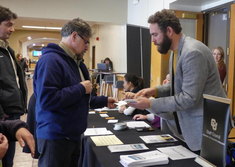 Two male staff members talking over a table at an event