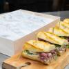 Row of sandwiches on wood plank