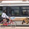 Buff bus with student on bike riding alongside