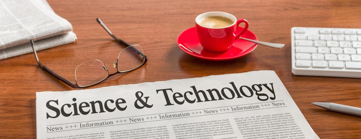 Science and Technology headline on a newspaper, next to eyeglasses and a computer
