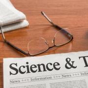 Science and Technology headline on a newspaper, next to eyeglasses and a computer