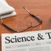 Science and Technology headline on a newspaper, next to eyeglasses and a computer