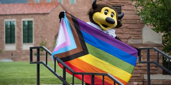 Chip the mascot holding a Pride flag on campus