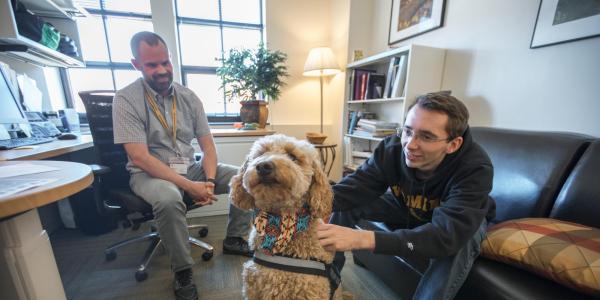 Counselor working with student and therapy dog