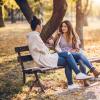 Two people talking on a bench outside