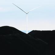 A wind turbine set in front of a blue sky 