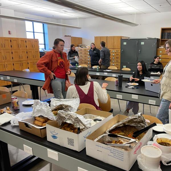 a group of people talking behind a food buffet