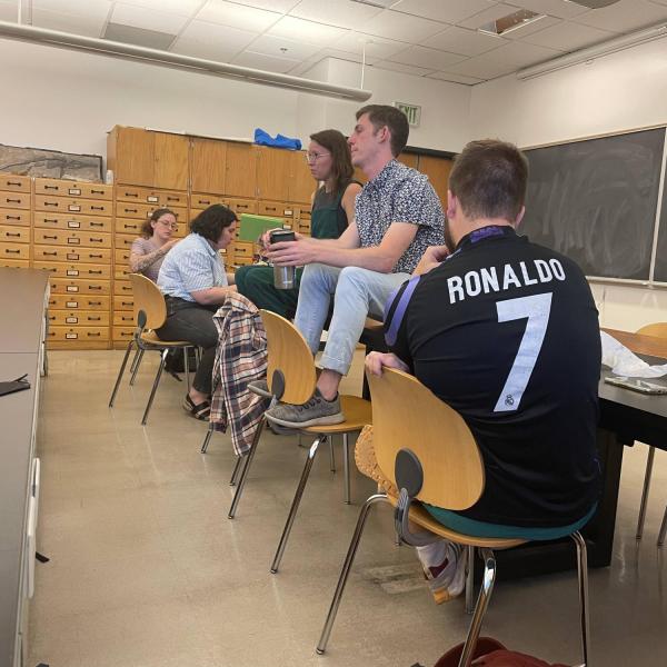 two people sitting on a desk talking to an audience