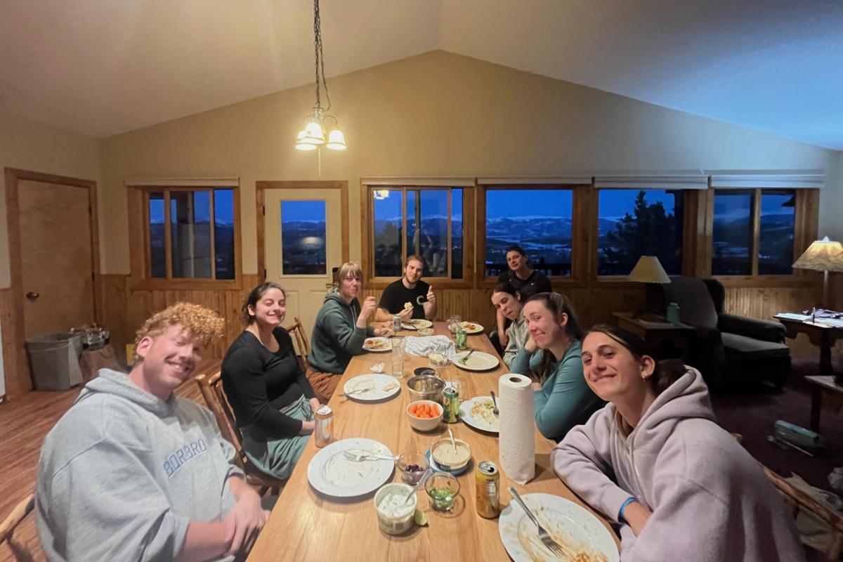 a group of people gathered around a dinner table in a cabin