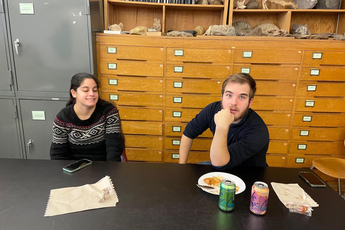 two people sitting at a table with empty plates looking at the camera