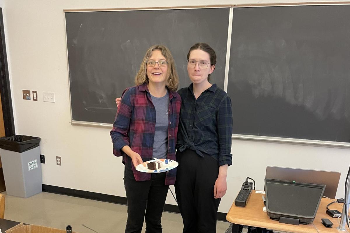 two women standing in front of a blackboard