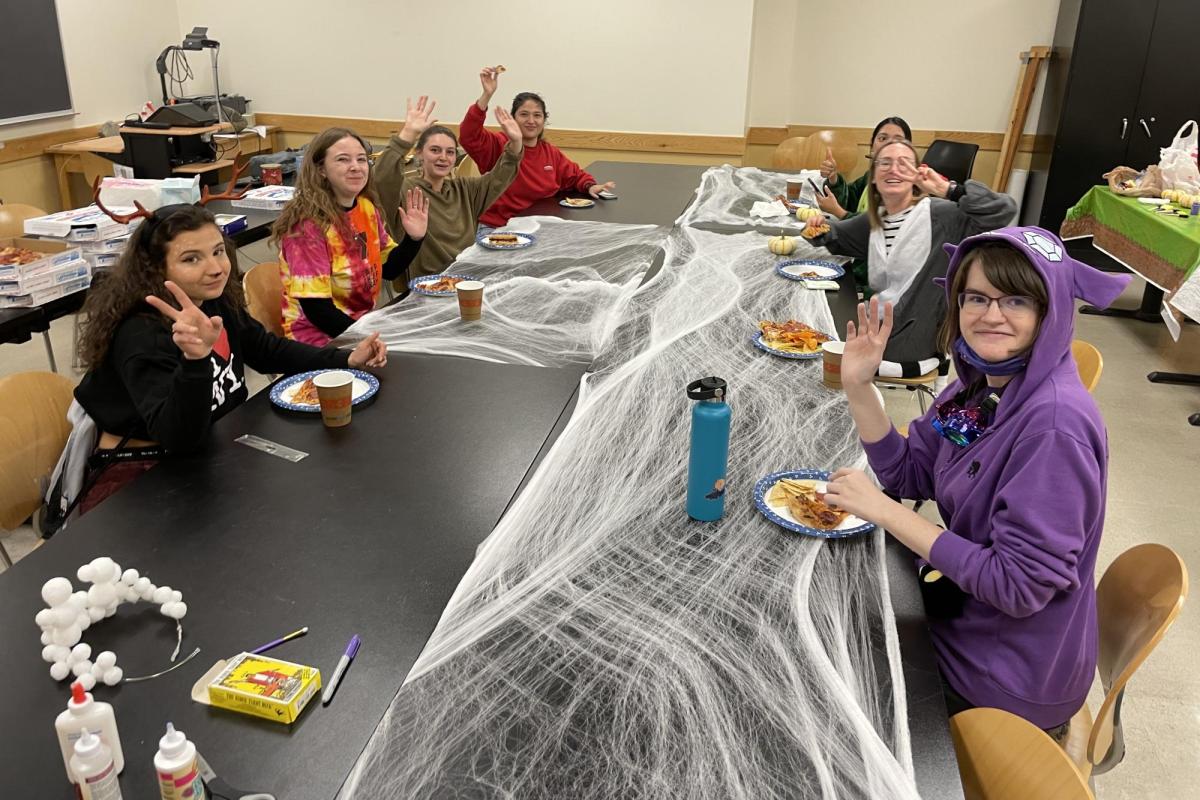 a diverse group of people in costumes eating pizza at a large table