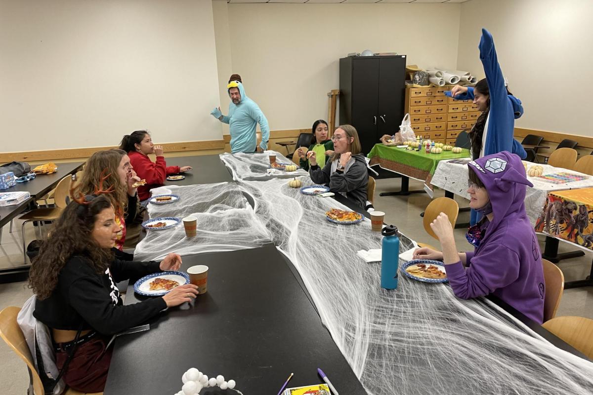 people in costumes eating pizza at a large table
