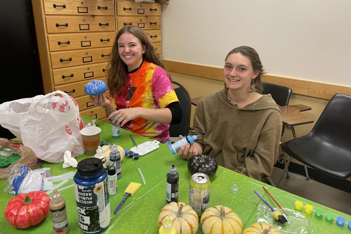 two women painting mini pumpkins