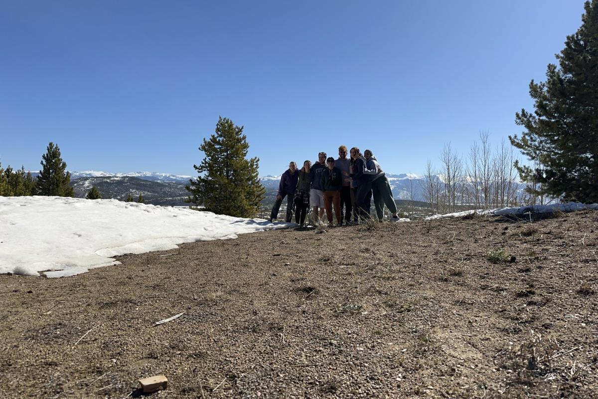 a group of people standing next to a patch of snow outside with blue skye