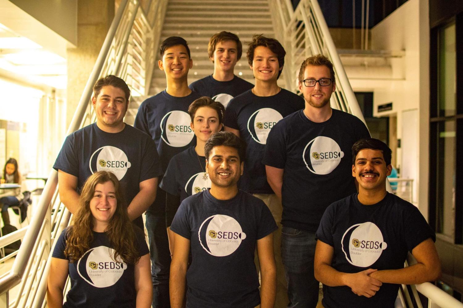 SEDS members in matching shirts posing in the Discovery Learning Center on main campus