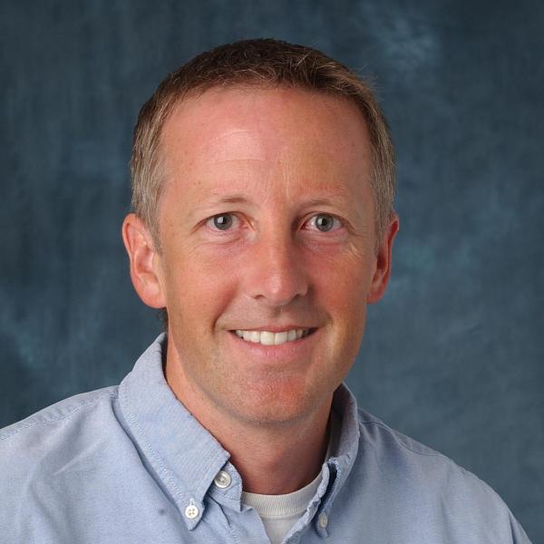 Photo of Chris, a light-skinned man wearing a light blue button-down shirt