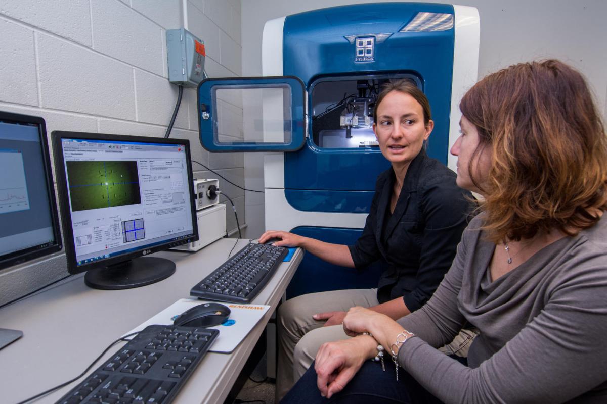 Two women discuss lab results shown on a computer.