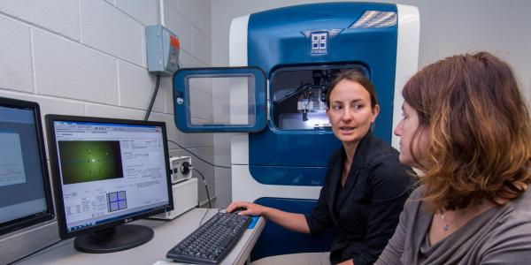 Two women discuss lab results shown on a computer.