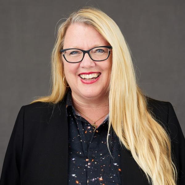 Image of Barbra Sobhani. Blond hair. Wearing a black blazer and a star themed shirt.