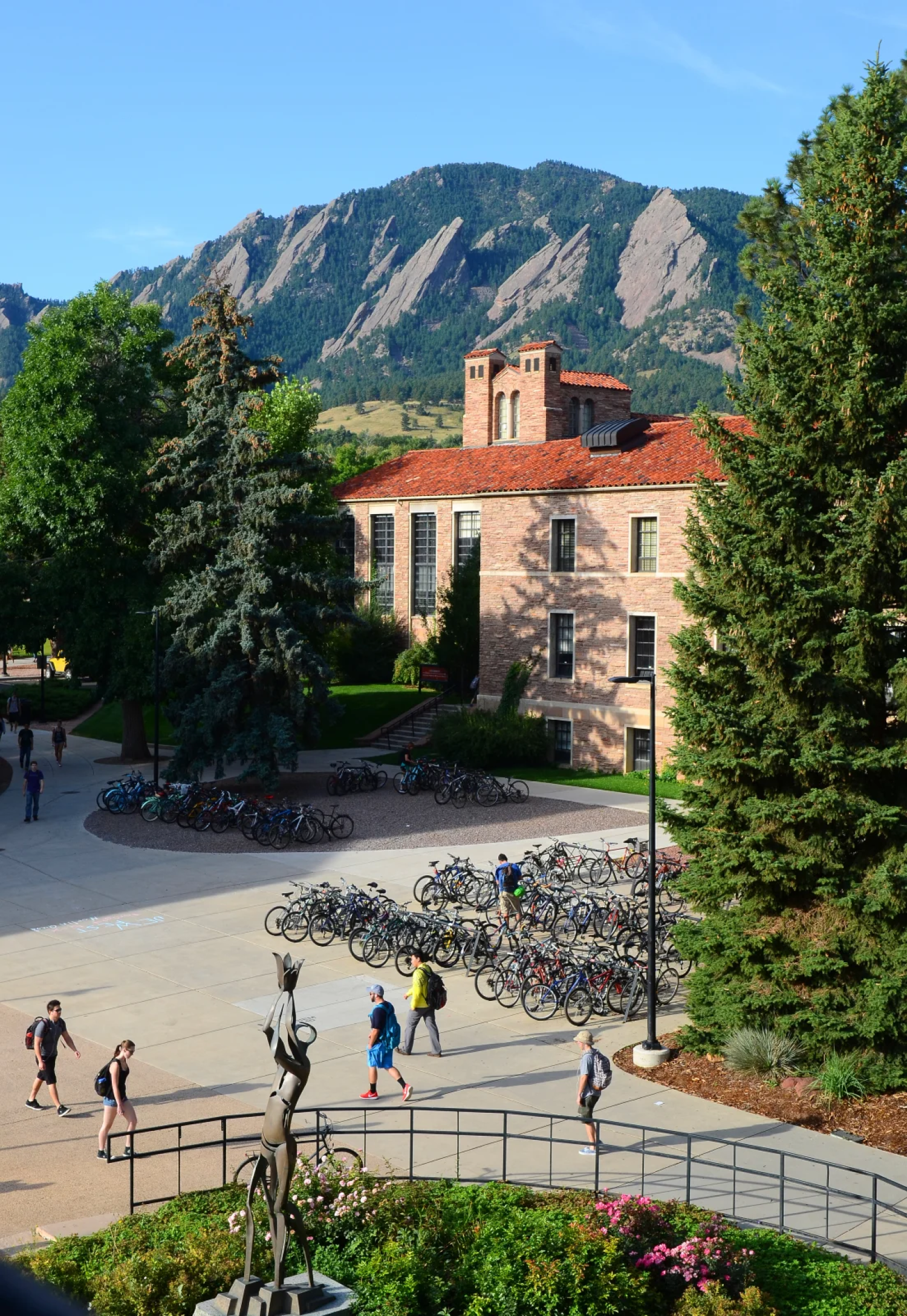 Students walking around campus with the flatirons in the background
