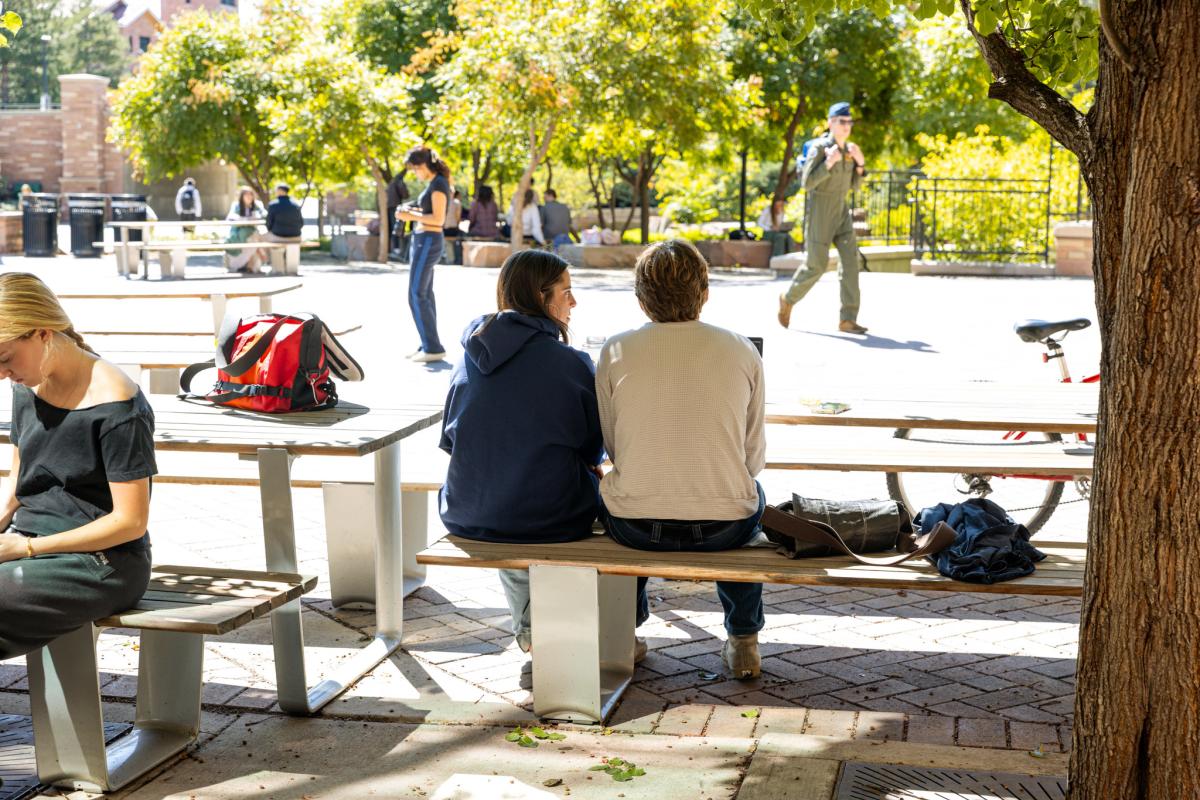 Two students sitting at a picnic table outside the Center for Community building