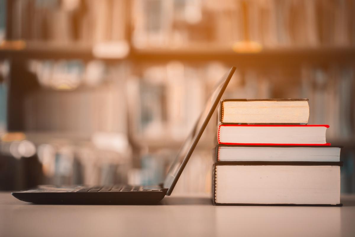 A laptop with some books sitting on a table