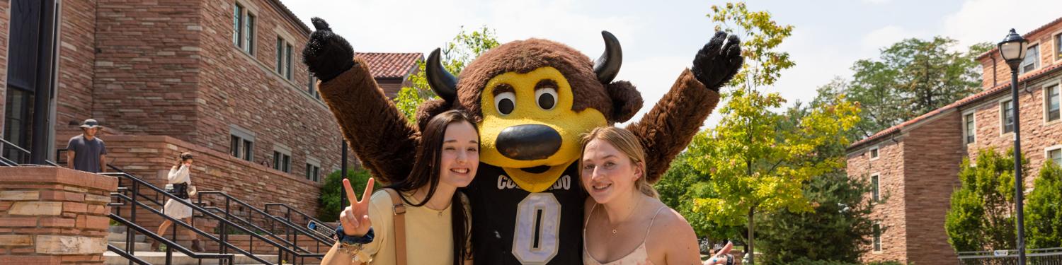 Two students pose for a photo with Chip during move-in