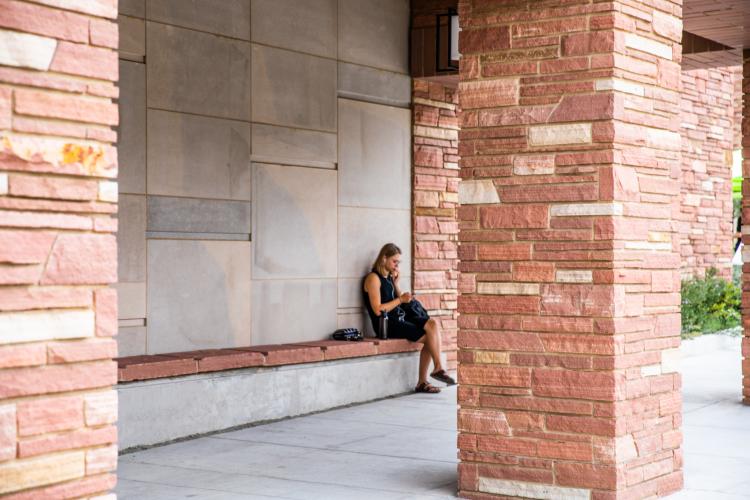 student sitting outside campus building