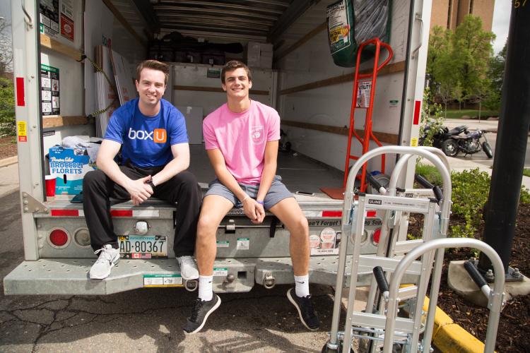 Two students sit in a moving truck