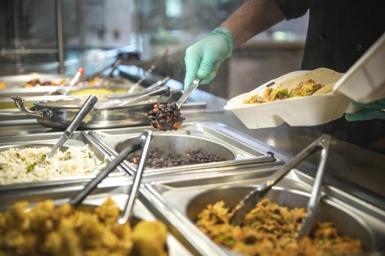 A Dining Services staff member adds food to a to-go container