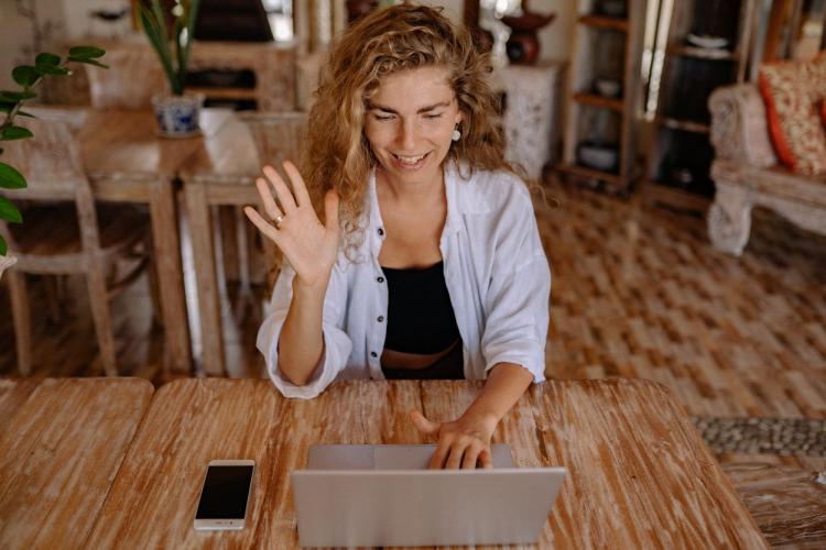 student waving to computer