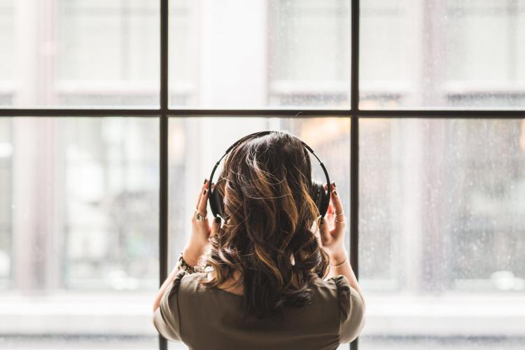 A girl with headphones on looking out a window