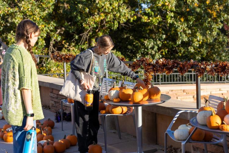 student next to a table of pumpkins