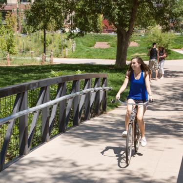 A student riding a bike on a bridge.