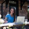 Student sitting outside with laptop and notebook.
